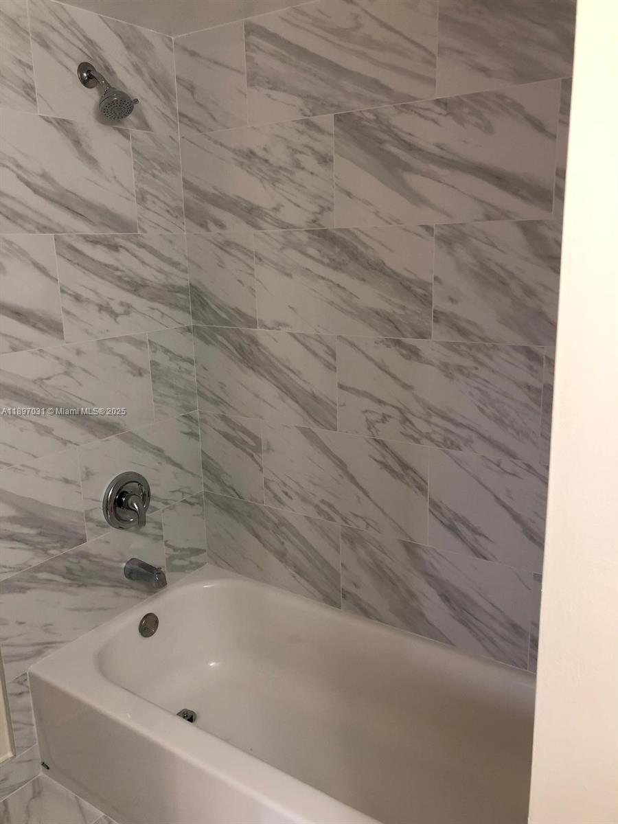A white bathtub is surrounded by walls featuring large-format, gray-veined marble-look tiles — 8401 SW 107th Ave # 313E, Miami FL 33173, MIAMI, FL