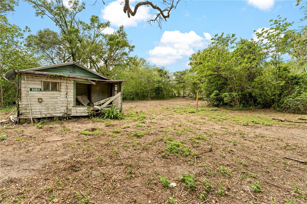 A dilapidated, white-sided wooden shed sits on a dirt lot surrounded by trees — 40611 OTIS ALLEN ROAD, ZEPHYRHILLS, FL