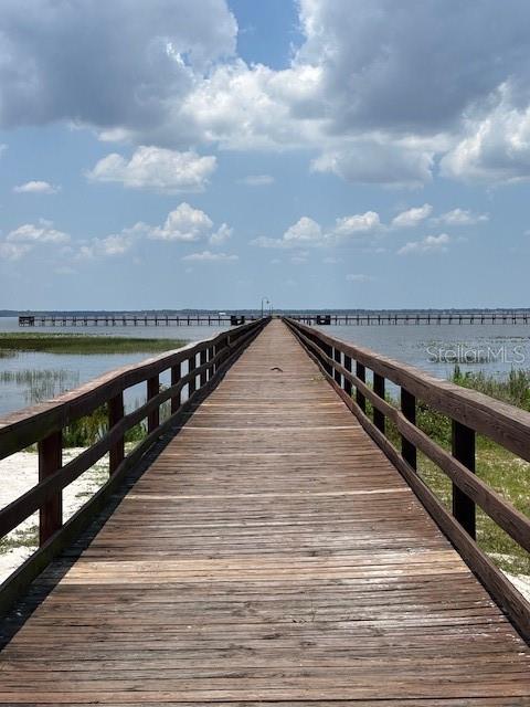 A long wooden pier extends over the water toward a distant bridge under a cloudy sky — 3061 AZALEA DRIVE, INDIAN LAKE ESTATES, FL