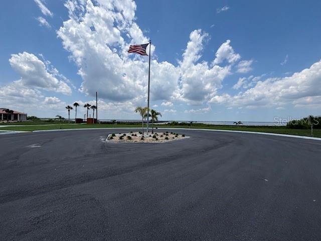 An American flag flies over a circular driveway with a landscaped center island near water — 3061 AZALEA DRIVE, INDIAN LAKE ESTATES, FL