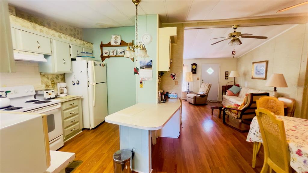 A kitchen with light green cabinets and a breakfast bar opens into a living area — 459 MARSHBURN DR, BRONSON, FL