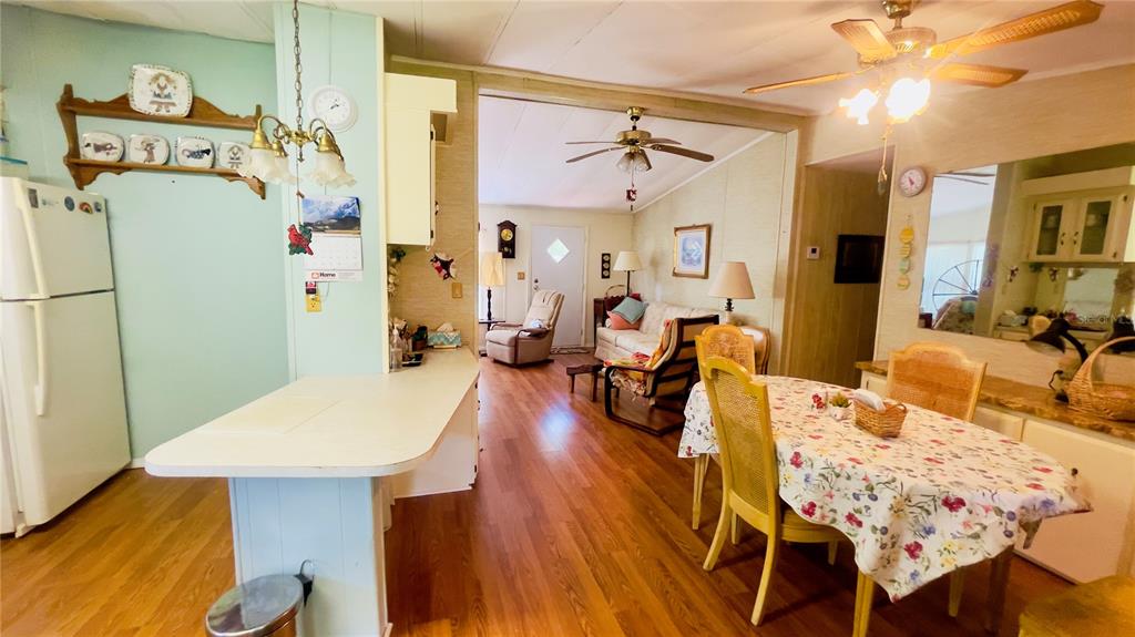 A kitchen with a breakfast bar opens into a living room with wood-look flooring — 459 MARSHBURN DR, BRONSON, FL