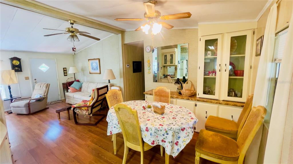 A dining area with a floral tablecloth and chairs sits adjacent to a living room — 459 MARSHBURN DR, BRONSON, FL