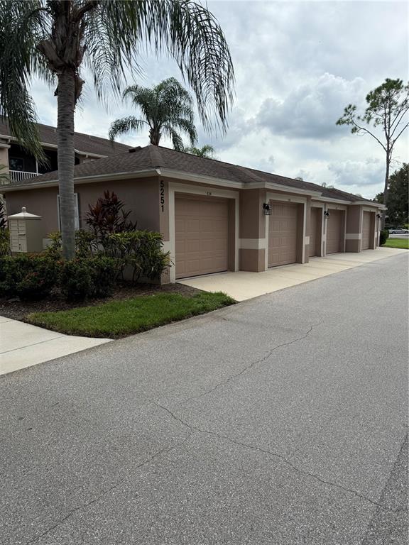A row of tan garage units with a palm tree and landscaping in the foreground — 5251 MAHOGANY RUN AVENUE UNIT 524, SARASOTA, FL