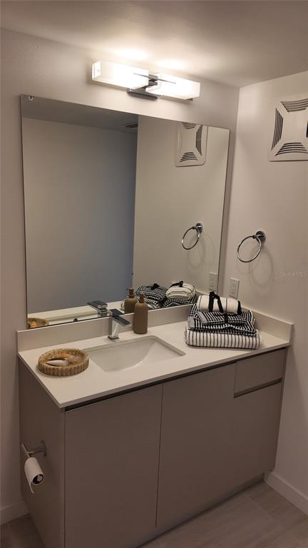 A modern bathroom vanity with a white countertop, rectangular sink, and large wall mirror — 5587 MILLENIA PARK BLVD UNIT 218, ORLANDO, FL