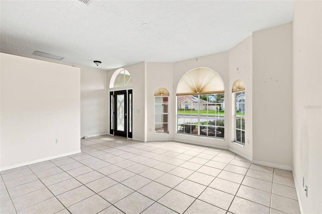 A bright, tiled living room features a front door and several arched windows — 934 PINE WALK COURT NE, PALM BAY, FL
