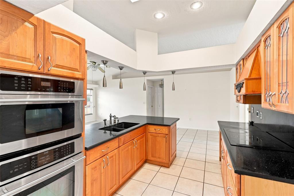A kitchen features wood cabinets, black countertops, stainless steel appliances, and tile flooring — 934 PINE WALK COURT NE, PALM BAY, FL