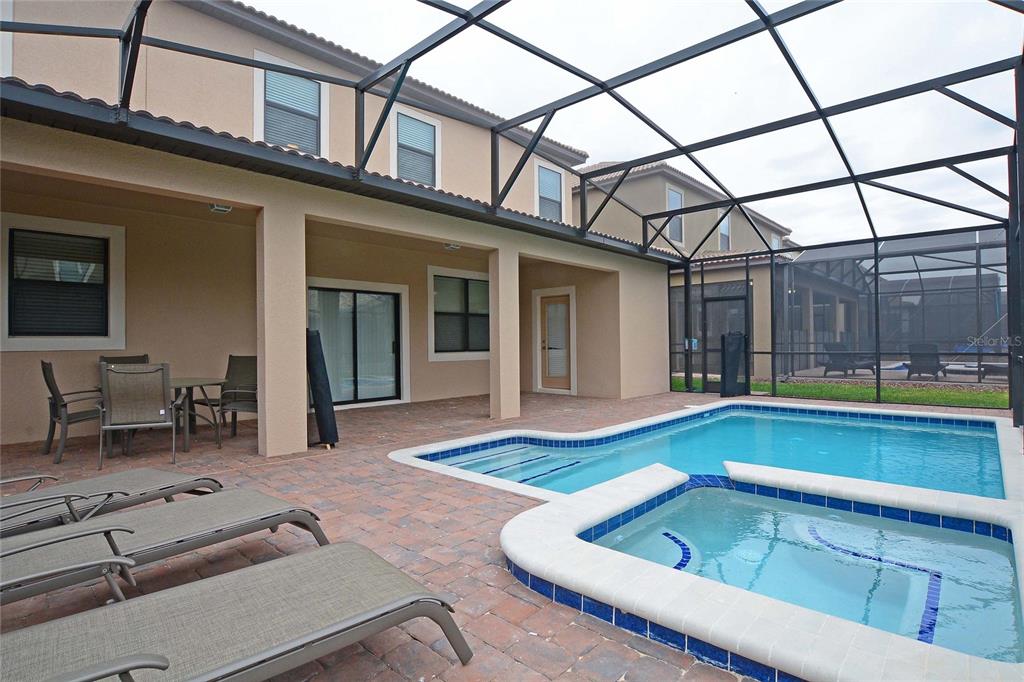 A screened-in patio features a swimming pool, a hot tub, and lounge chairs — 1469 MOON VALLEY DRIVE, DAVENPORT, FL