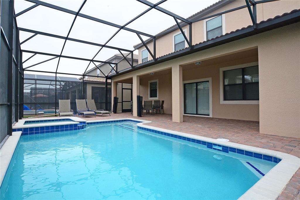 A screened-in patio features a swimming pool with an attached spa and brick pavers — 1469 MOON VALLEY DRIVE, DAVENPORT, FL