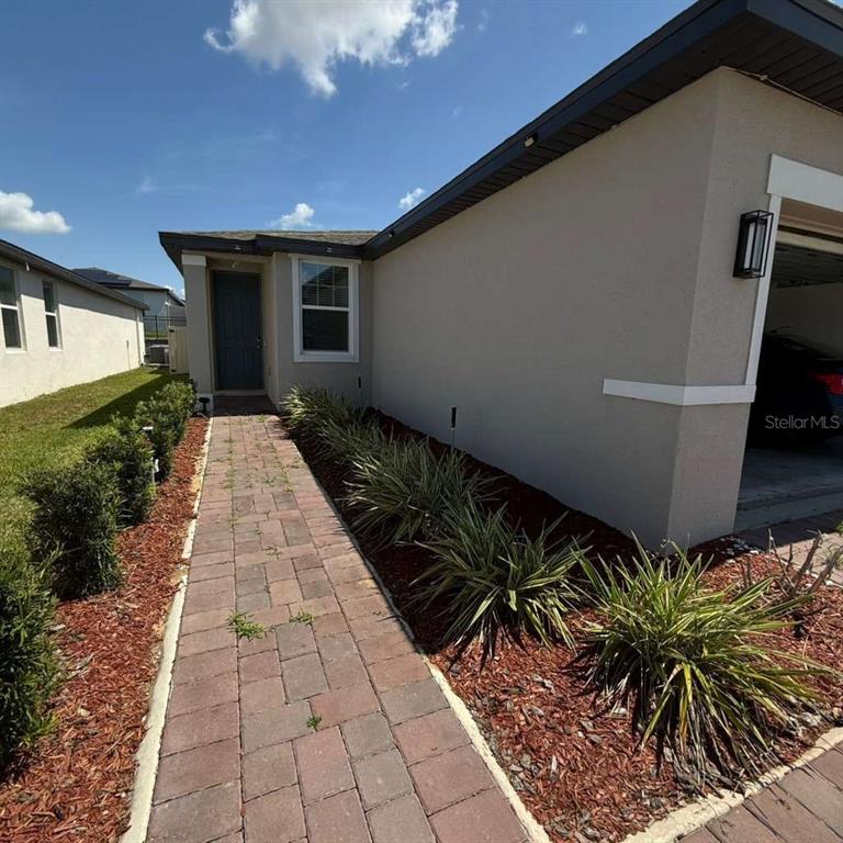 A paved walkway leads to the front entrance of a house with a side garage — 1445 SEA GLASS ROAD, HAINES CITY, FL