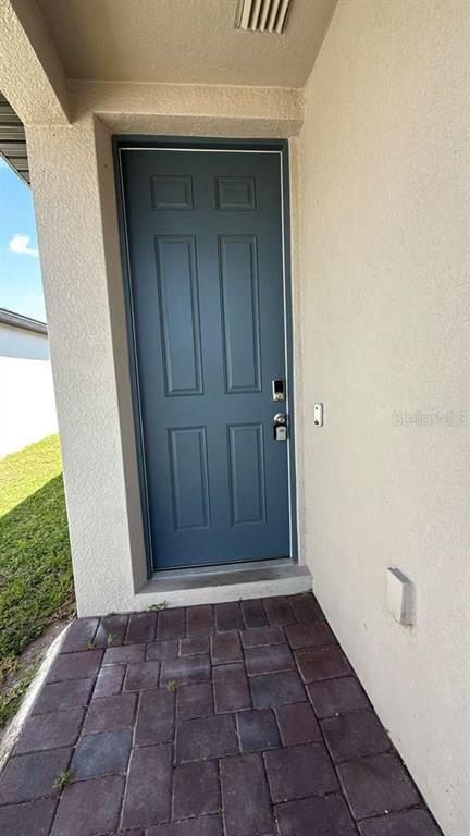 A blue front door with a keypad lock sits at the end of a paved walkway — 1445 SEA GLASS ROAD, HAINES CITY, FL
