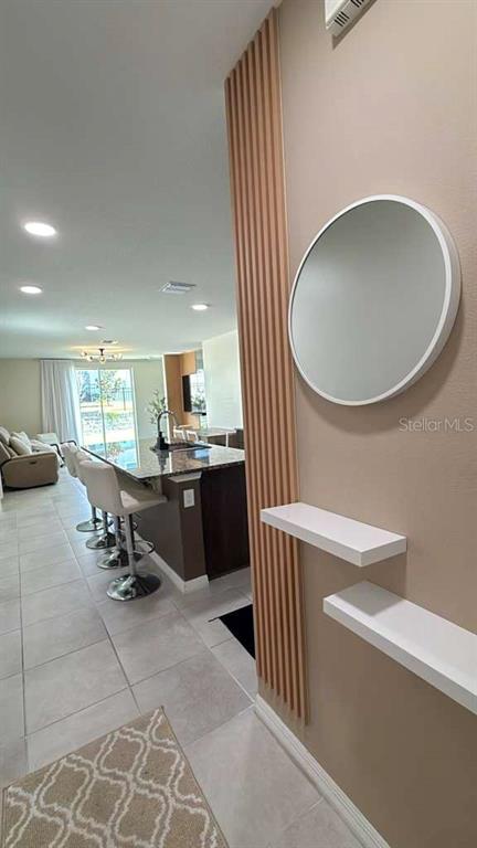 A kitchen with a breakfast bar and stools sits beside a wall with floating shelves — 1445 SEA GLASS ROAD, HAINES CITY, FL