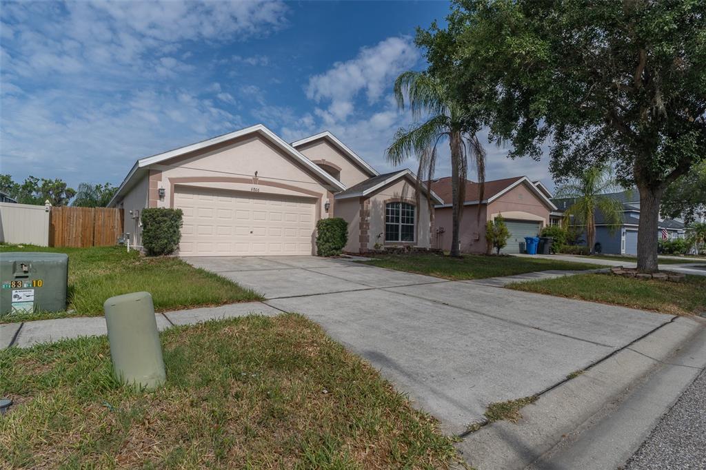 A single-story suburban house with a two-car garage and a concrete driveway — 6806 GUILFORD CREST DRIVE, APOLLO BEACH, FL