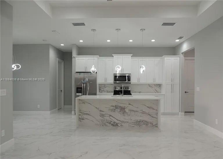 A modern kitchen features white cabinetry, a marble-patterned island, and matching marble-look tile flooring — 2011 NW 10 PL, Cape Coral FL 33993, CAPE CORAL, FL
