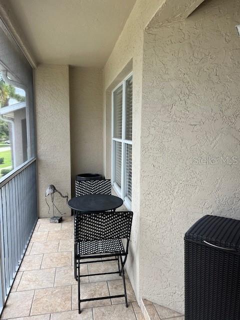 A covered balcony features tiled flooring, a small round table with two chairs, and a screen — 5270 HYLAND HILLS AVENUE UNIT 1724, SARASOTA, FL