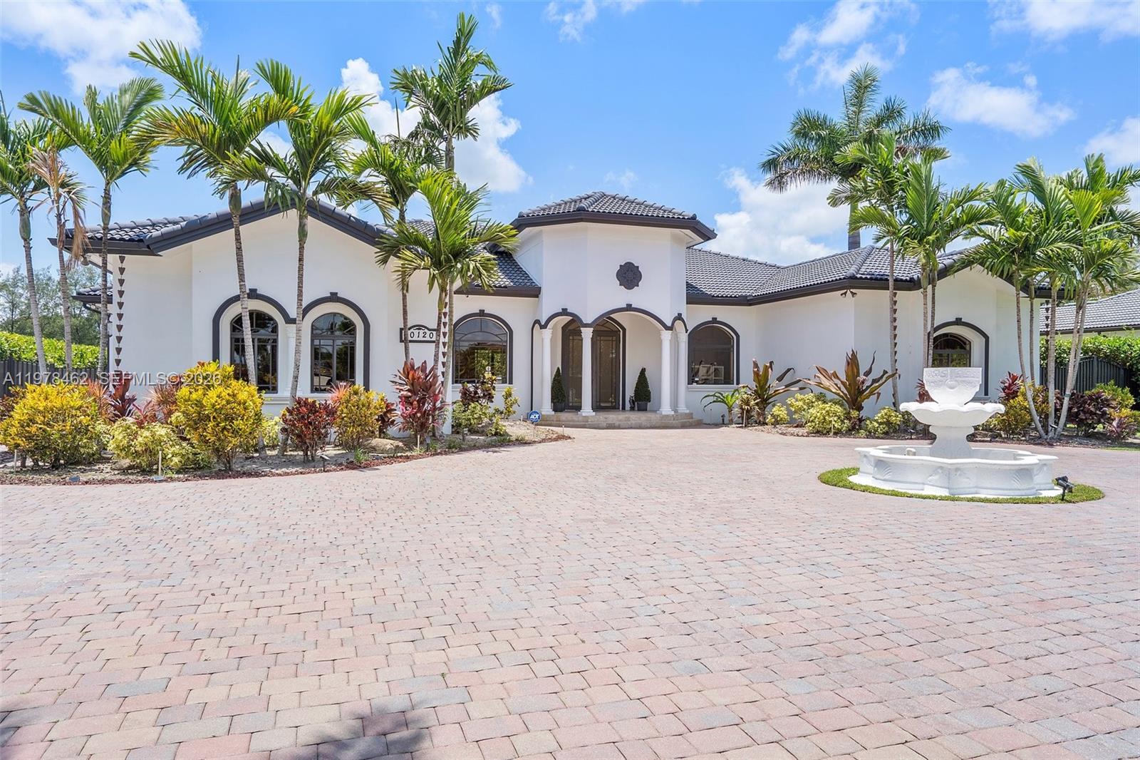 A single-story white house with a tiled roof, arched windows, and a circular driveway fountain — 20120 SW 133rd Ave, Miami FL 33177, MIAMI, FL