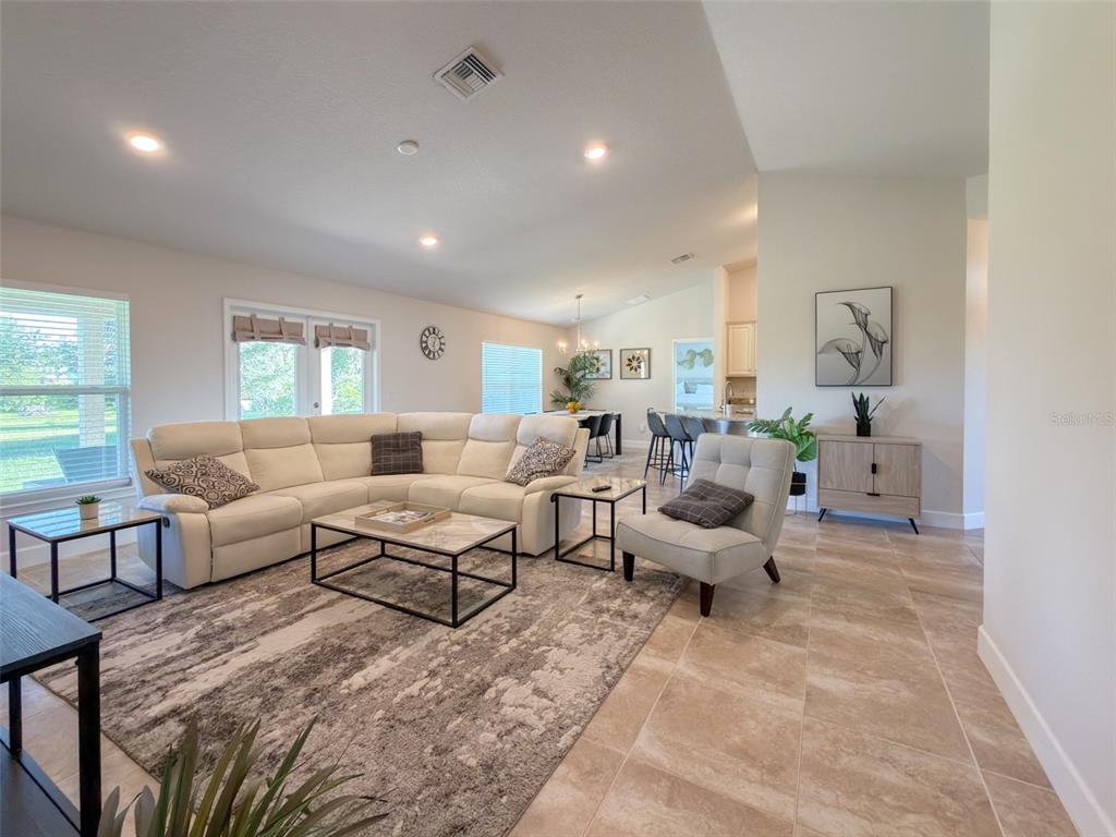 A bright open-concept living room features a large sectional sofa, tile flooring, and dining area — 249 ROTONDA BOULEVARD W, ROTONDA WEST, FL