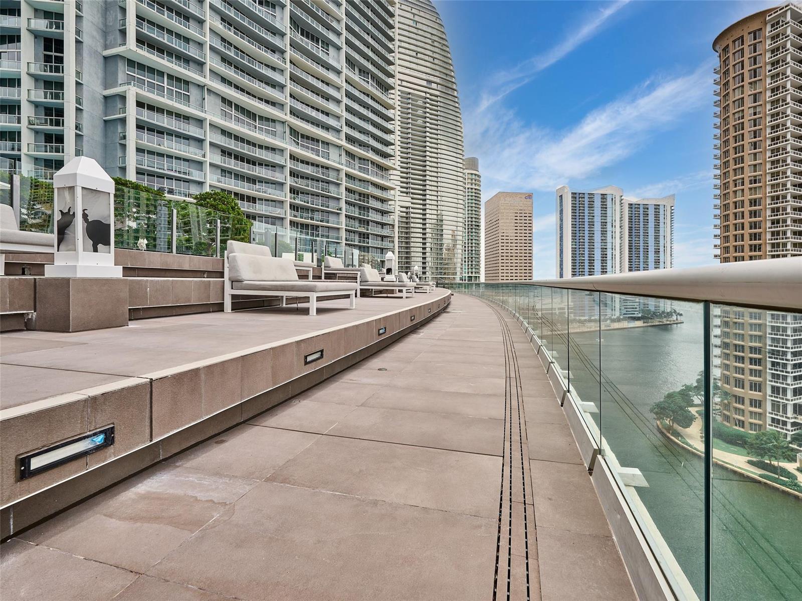 A curved outdoor terrace features lounge chairs, glass railings, and views of surrounding high-rise buildings — 495 Brickell Avenue # 4506, Miami FL 33131, MIAMI, FL