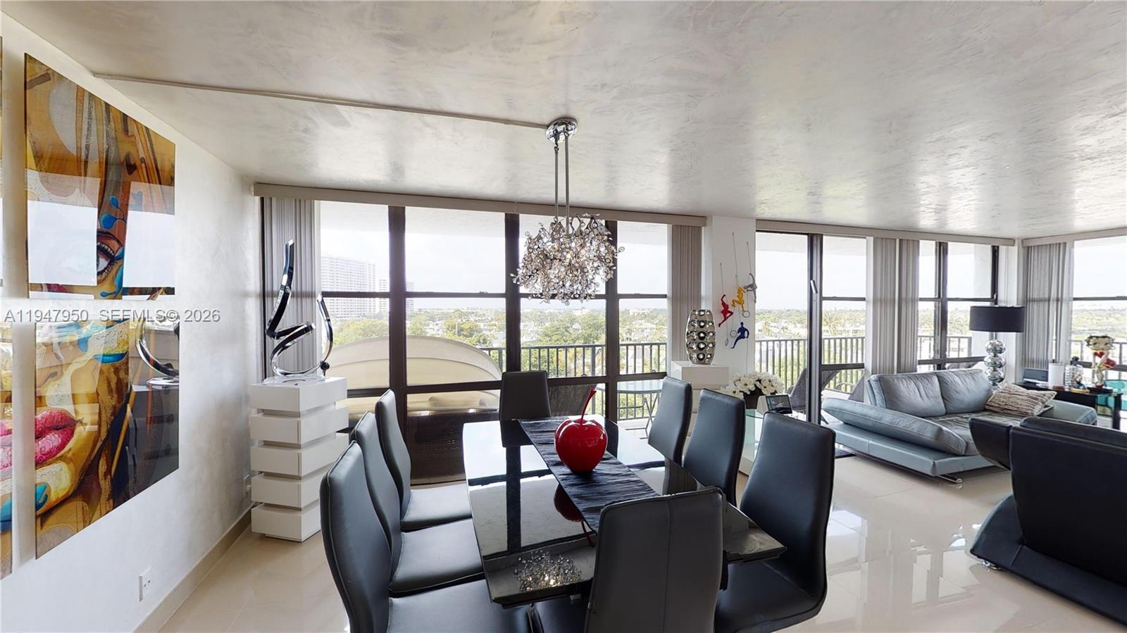 A dining area with a black table and chairs sits before floor-to-ceiling windows — 800 Parkview Dr # 709, Hallandale Beach FL 33009, HALLANDALE BEACH, FL