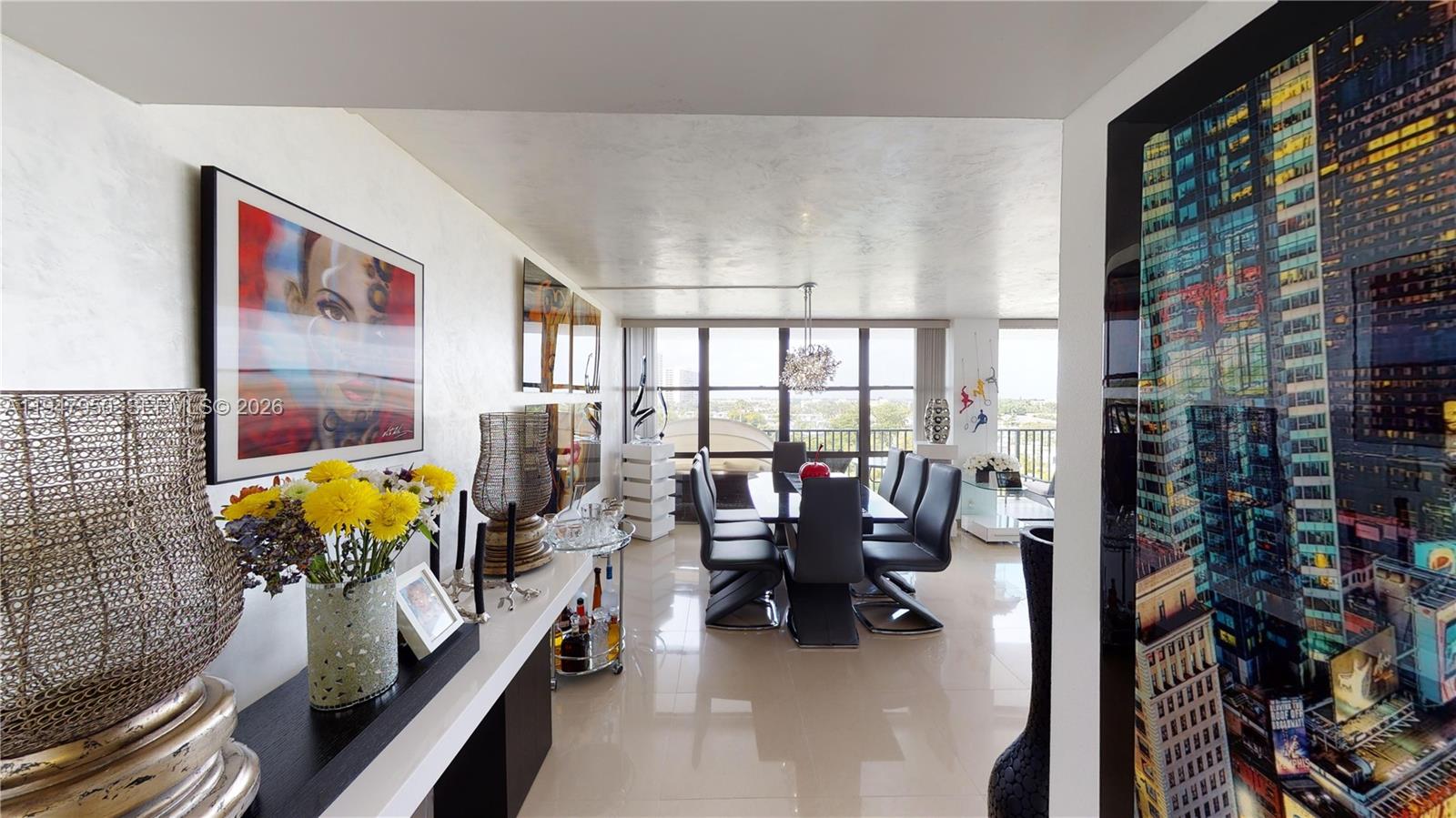 A modern dining room features a glass table, dark chairs, and large wall art — 800 Parkview Dr # 709, Hallandale Beach FL 33009, HALLANDALE BEACH, FL