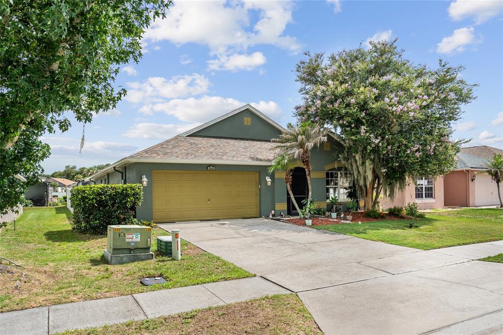 A single-story house with a green exterior, a two-car garage, and a front yard — 3049 MERLOT WAY, CLERMONT, FL