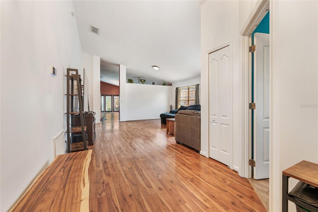 A living room features hardwood flooring, a vaulted ceiling, and a white closet door — 3049 MERLOT WAY, CLERMONT, FL