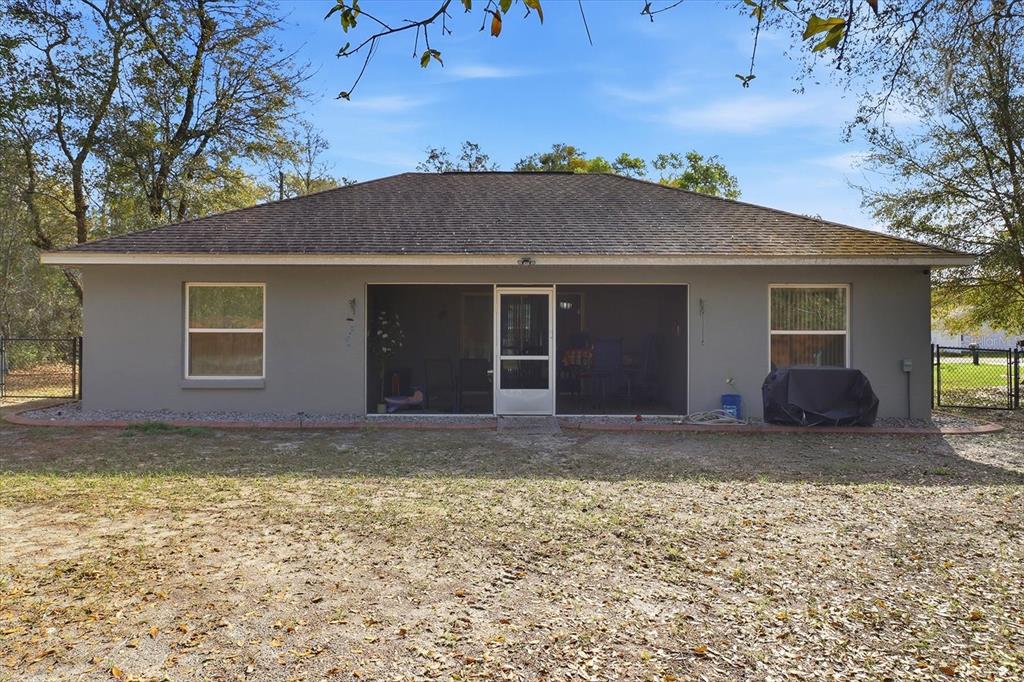The rear exterior of a gray house features a screened-in porch and two windows — 786 N DUGAN AVENUE, INVERNESS, FL