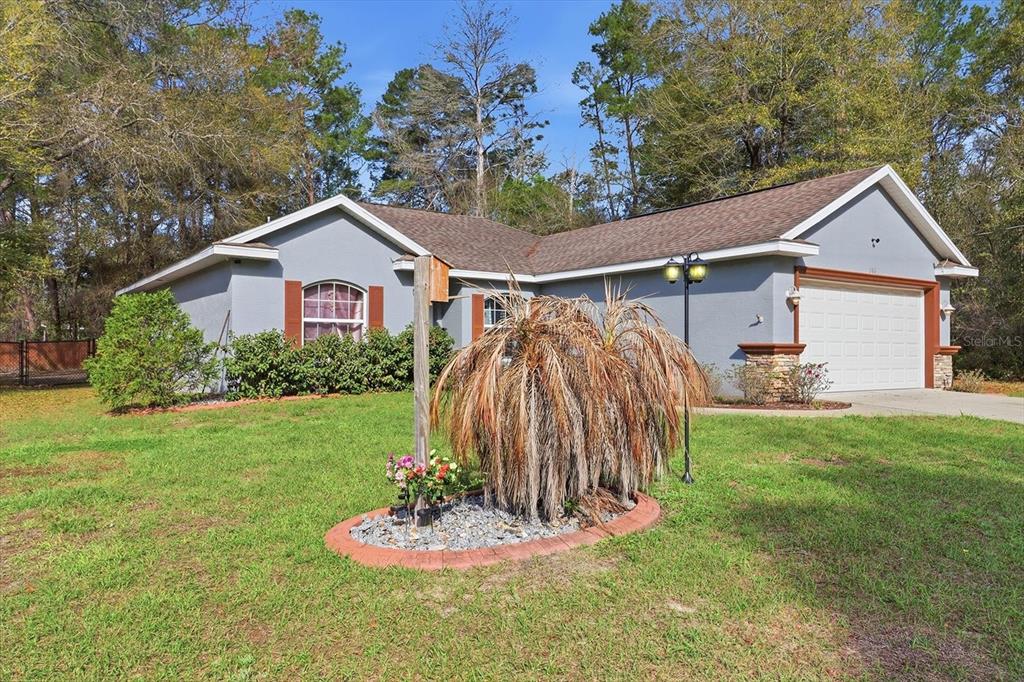 A single-story house with a gray exterior, brown roof, and a front yard garden bed — 786 N DUGAN AVENUE, INVERNESS, FL