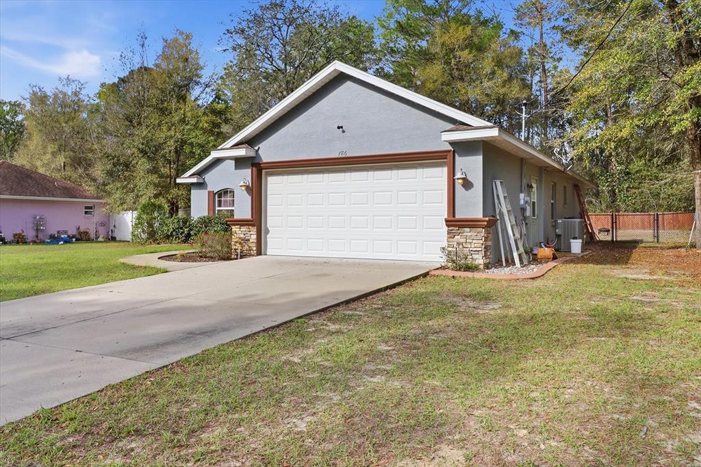 A gray single-story house with a two-car garage, stone accents, and a concrete driveway — 786 N DUGAN AVENUE, INVERNESS, FL