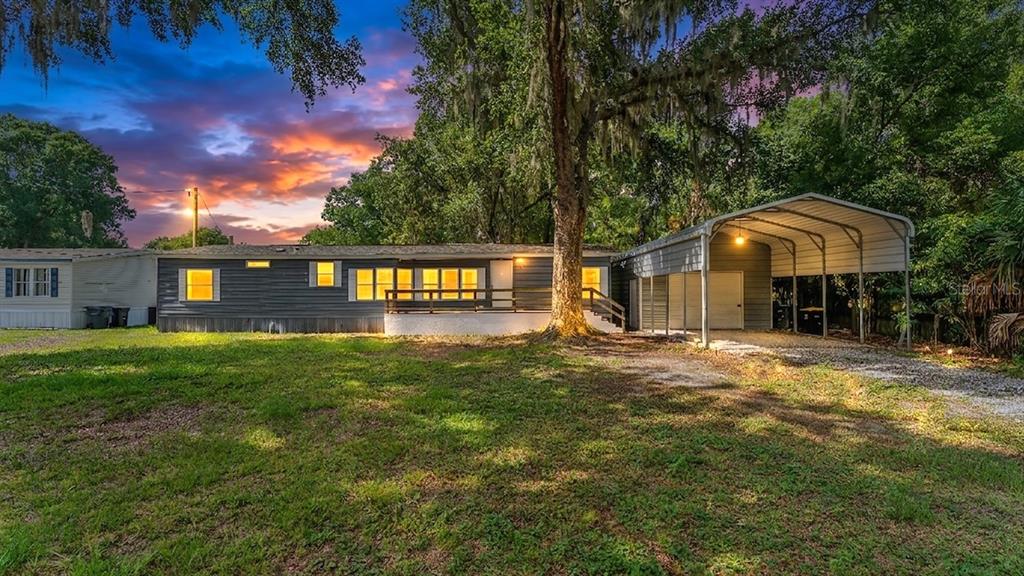 A dark gray manufactured home with a front deck and an attached metal carport — 509 SHARON HILL COURT, WINTER HAVEN, FL