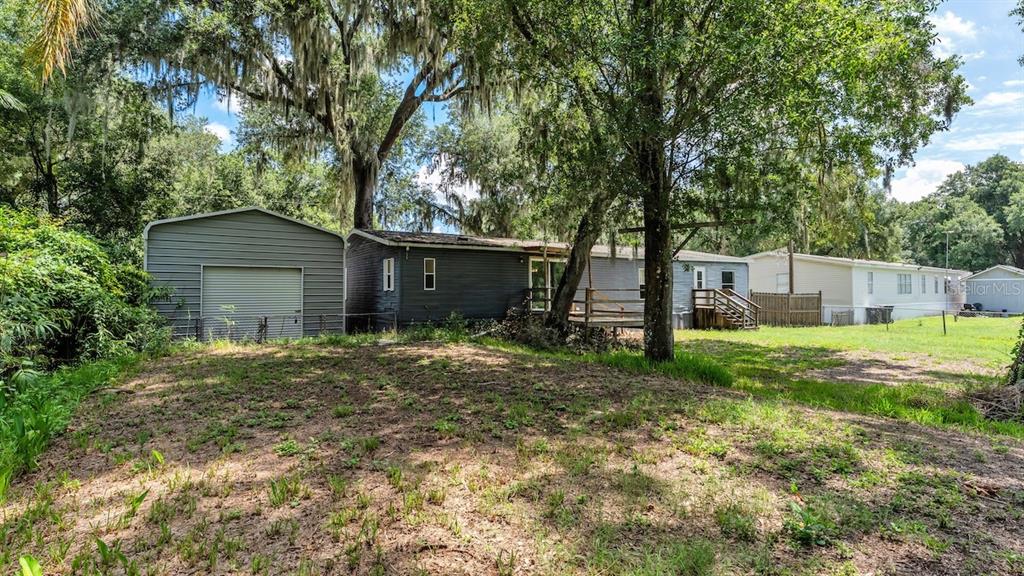 A detached metal garage stands next to a mobile home with a wooden deck — 509 SHARON HILL COURT, WINTER HAVEN, FL
