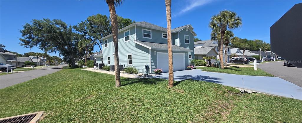 A two-story light blue house with a garage and palm trees in a suburban neighborhood — 68 BRISTOL LANE, PALM COAST, FL