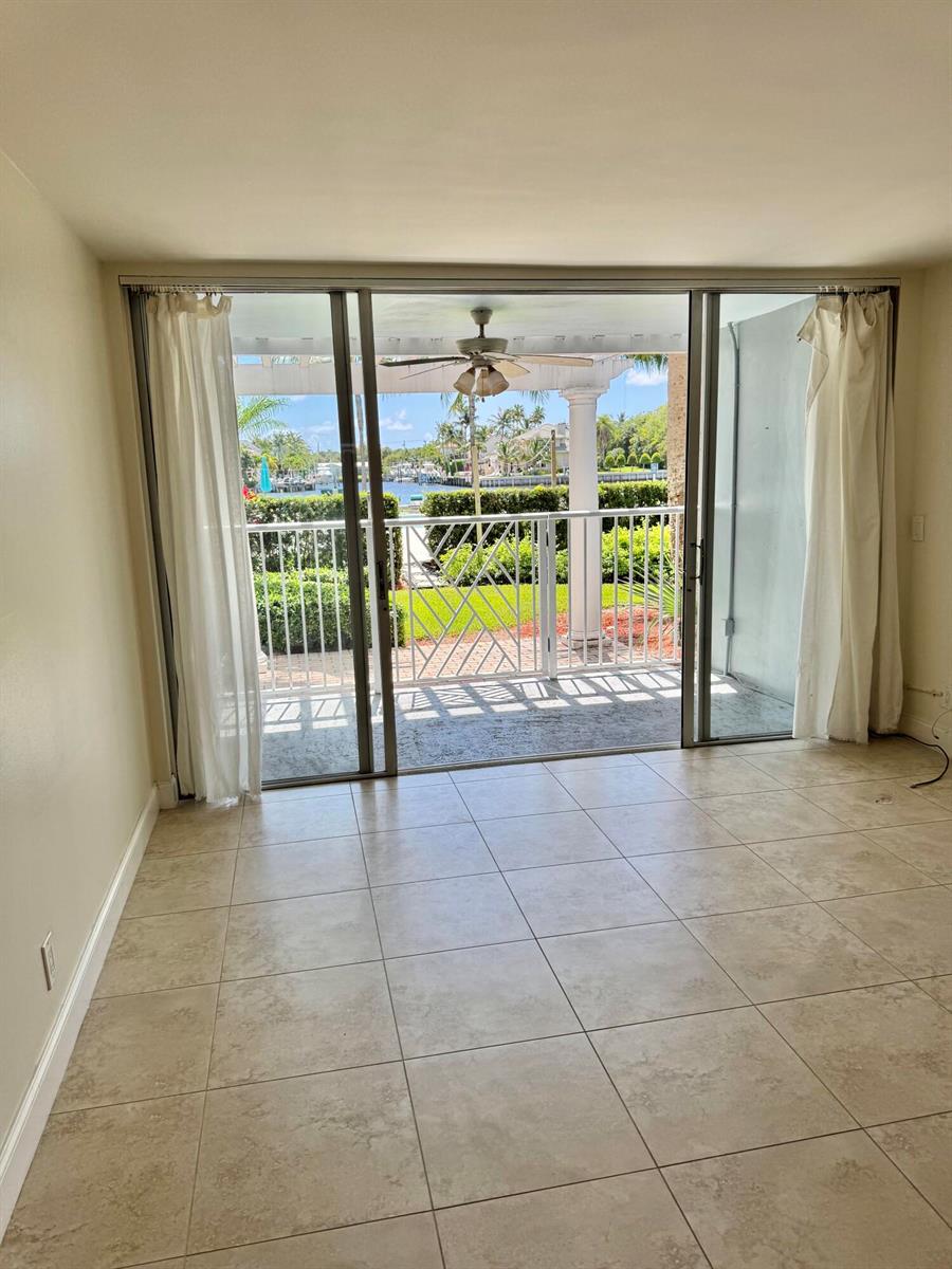 A room with light-colored tile flooring features a large sliding glass door opening to a patio — 651 E Woolbright Road # 103, Boynton Beach FL 33435, BOYNTON BEACH, FL