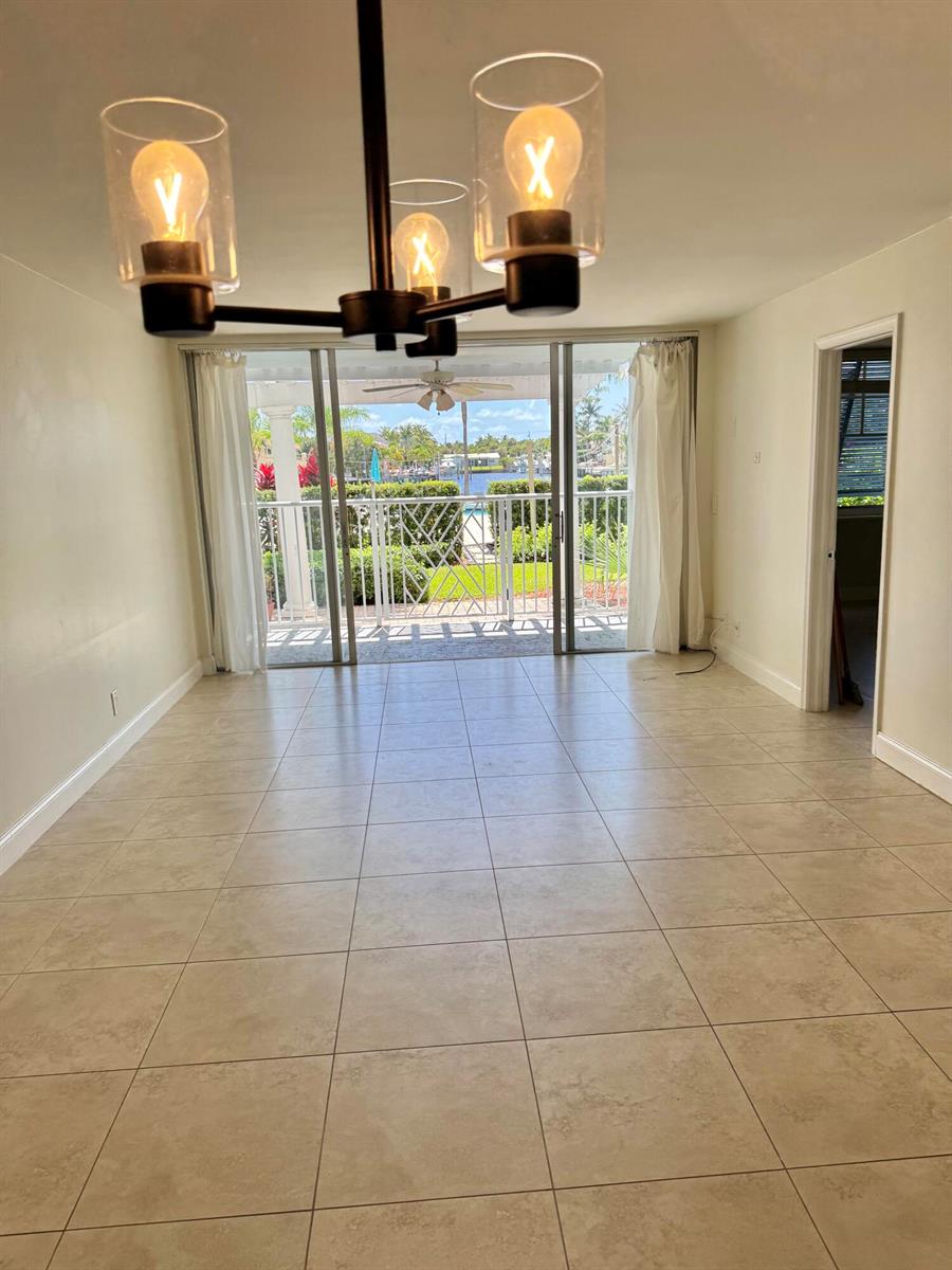 An empty dining area with tile flooring, a modern chandelier, and sliding doors to a patio — 651 E Woolbright Road # 103, Boynton Beach FL 33435, BOYNTON BEACH, FL