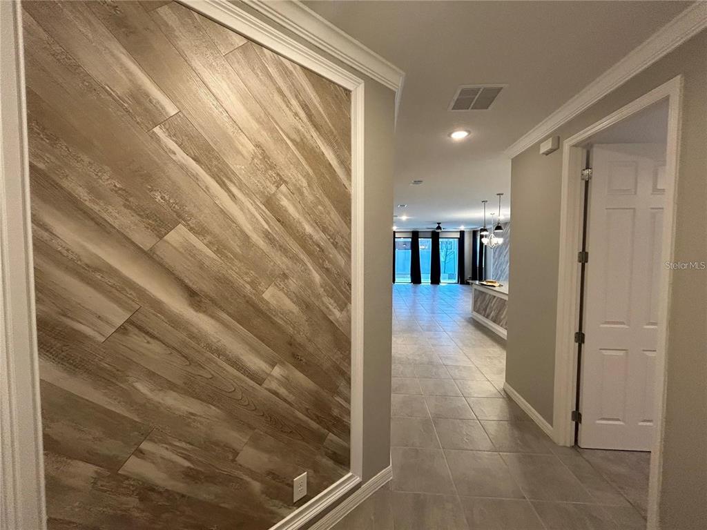A hallway features a wood-plank accent wall and leads into an open-concept living area — 4111 SOLAMOR STREET, LAKELAND, FL