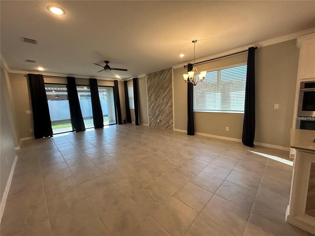 An open-concept living and dining area features tile flooring, a ceiling fan, and large windows — 4111 SOLAMOR STREET, LAKELAND, FL