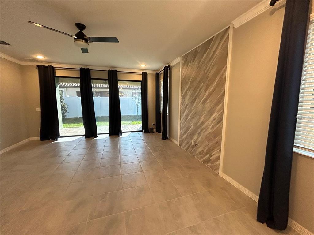 A living room features large tile flooring, a wood-look accent wall, and sliding glass doors — 4111 SOLAMOR STREET, LAKELAND, FL