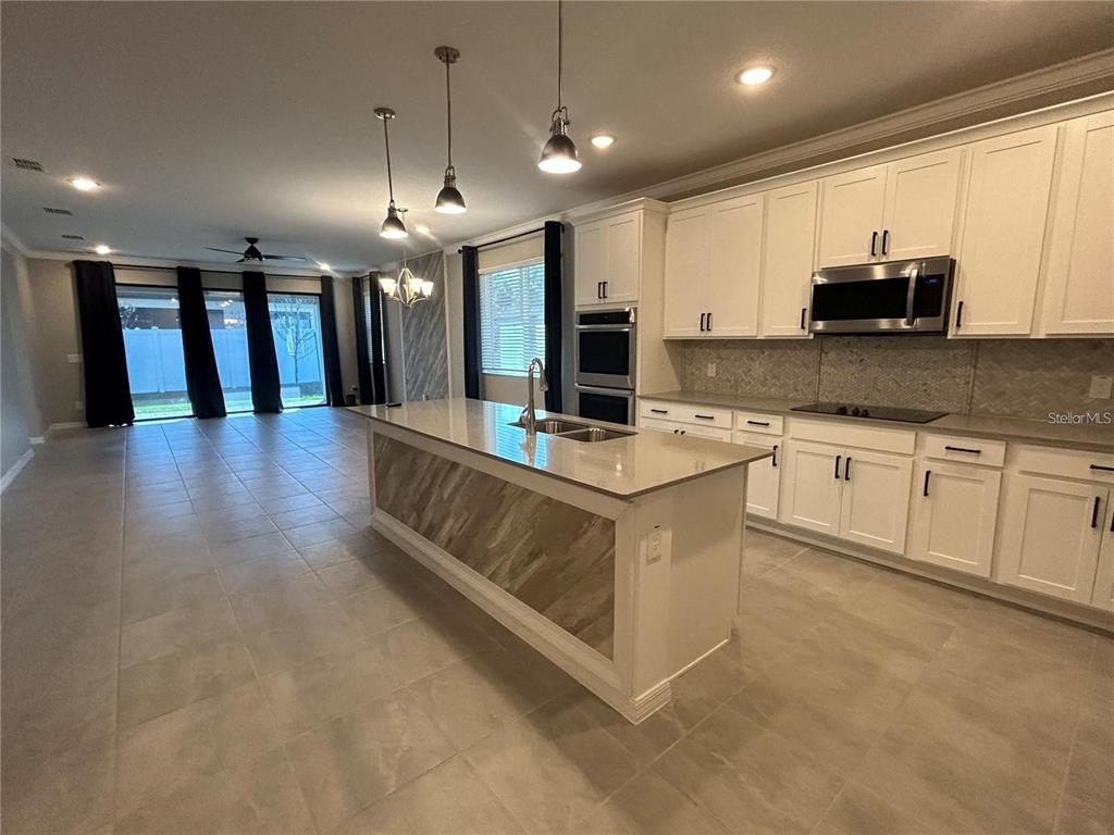 A kitchen features white cabinetry, a large island with a sink, and tile flooring — 4111 SOLAMOR STREET, LAKELAND, FL