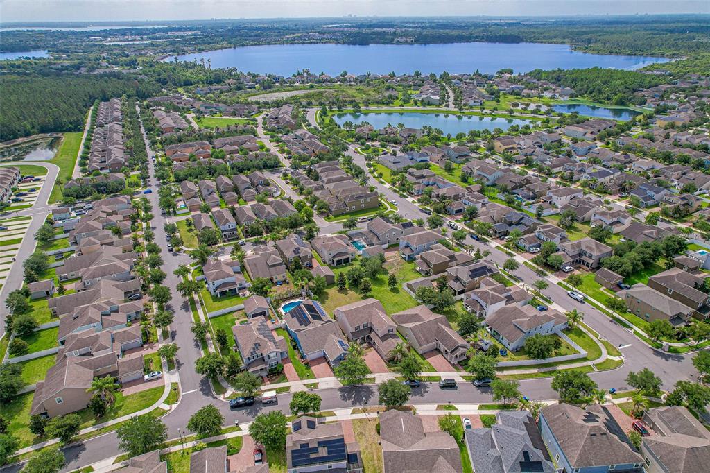 An aerial view shows a suburban neighborhood with houses, swimming pools, and a large lake — 5973 CYPRESS HILL ROAD, WINTER GARDEN, FL