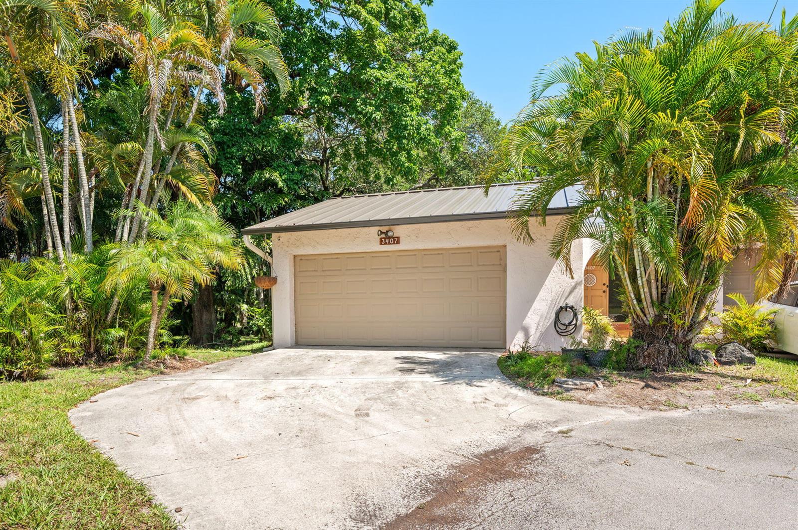 A beige garage with a metal roof sits at the end of a concrete driveway — 3407 Cherry Garden Circle # 151, Lauderhill FL 33319, LAUDERHILL, FL