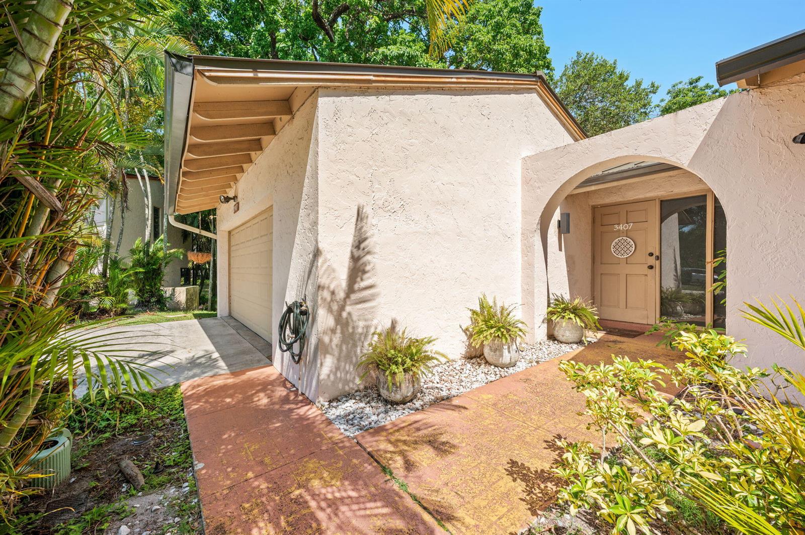 A beige stucco house exterior features a garage, an arched entryway, and a paved walkway — 3407 Cherry Garden Circle # 151, Lauderhill FL 33319, LAUDERHILL, FL