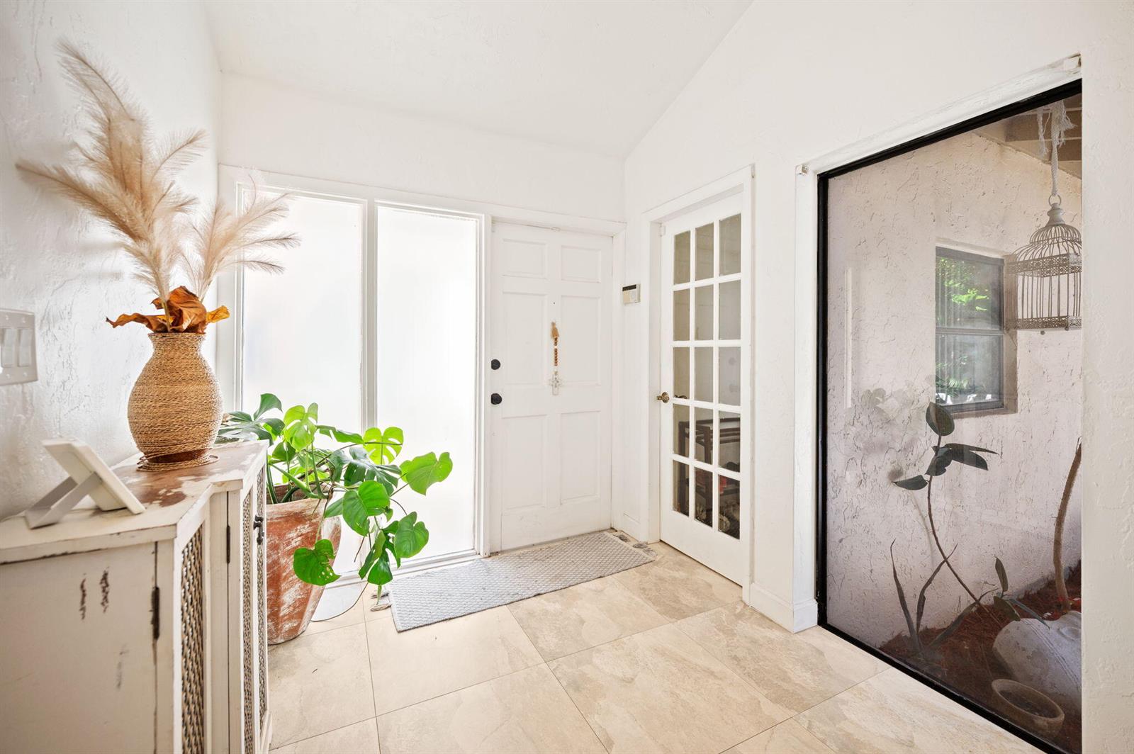 A bright entryway features white walls, tile flooring, a glass-paned door, and a large window — 3407 Cherry Garden Circle # 151, Lauderhill FL 33319, LAUDERHILL, FL