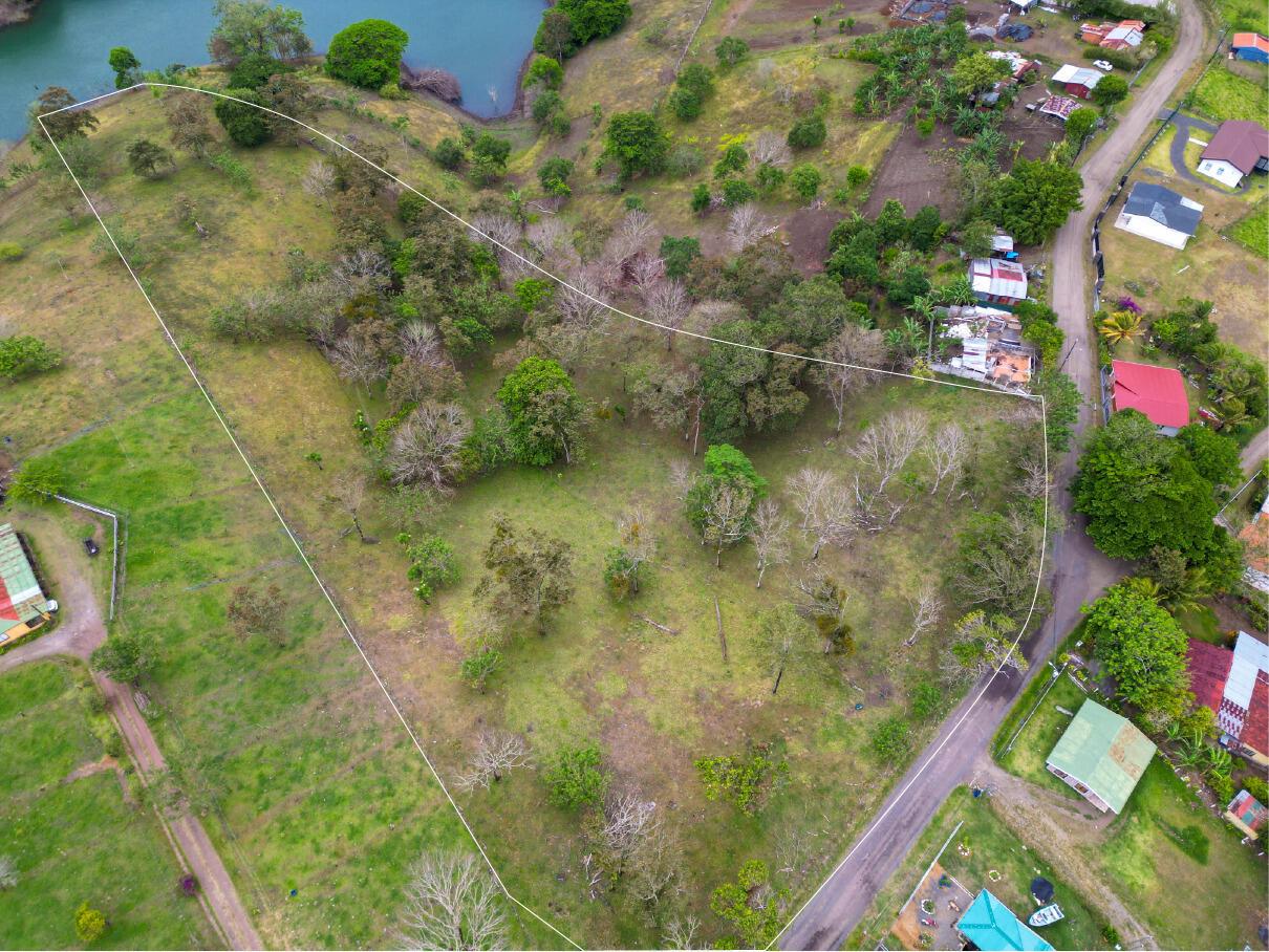 An aerial view shows a grassy, tree-dotted plot of land outlined in white near water — Lot 7 Guanacaste Province, Tronadora, FL