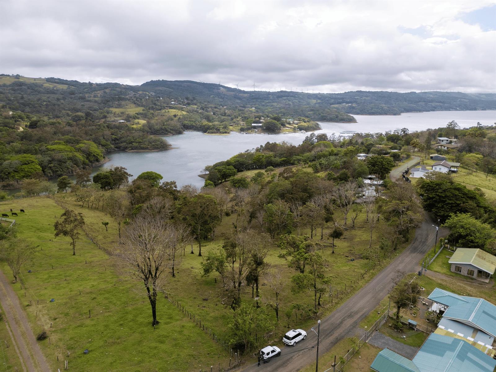 An aerial view shows a rural landscape with a lake, rolling hills, and a road — Lot 7 Guanacaste Province, Tronadora, FL