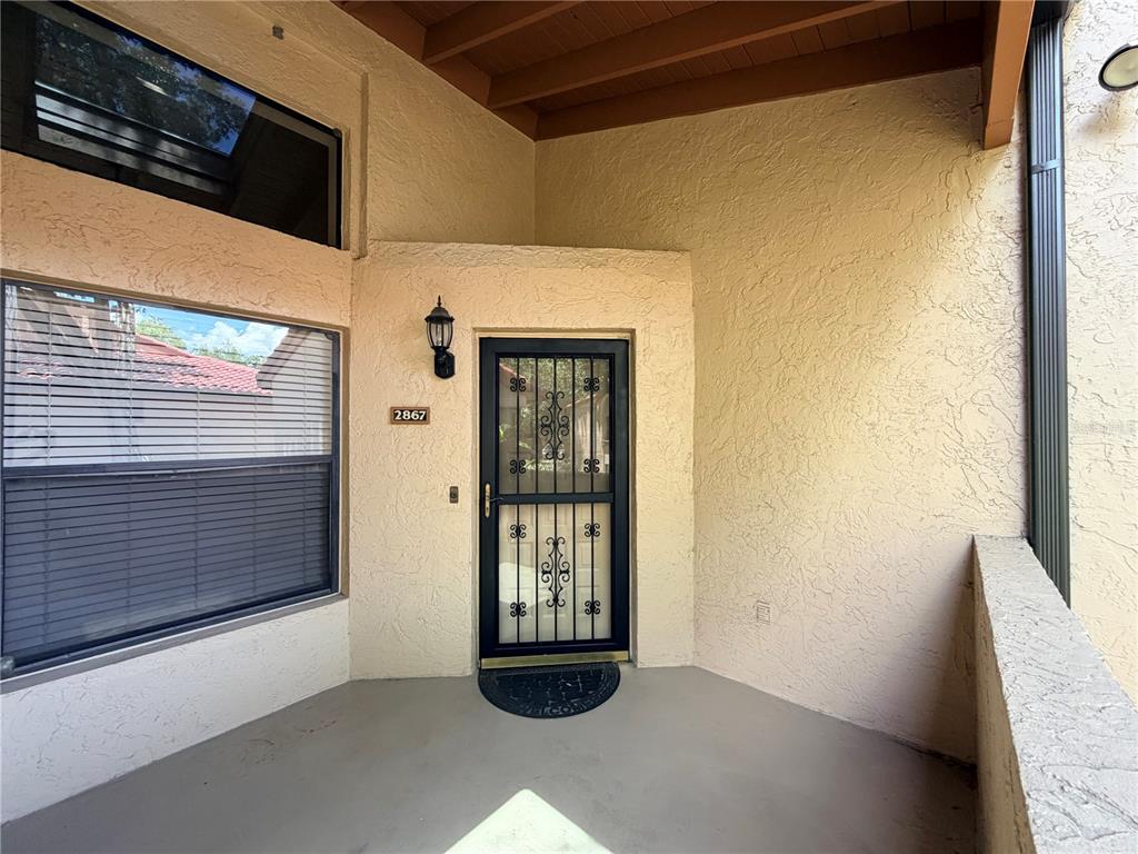 The exterior entryway features a textured beige wall, a black security door, and two windows — 2867 MARSALA COURT UNIT 2867, ORLANDO, FL