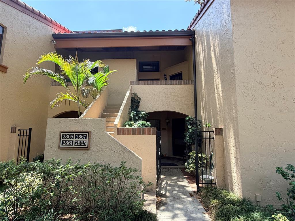 The exterior of a two-story stucco building features a staircase leading to upper-level units — 2867 MARSALA COURT UNIT 2867, ORLANDO, FL