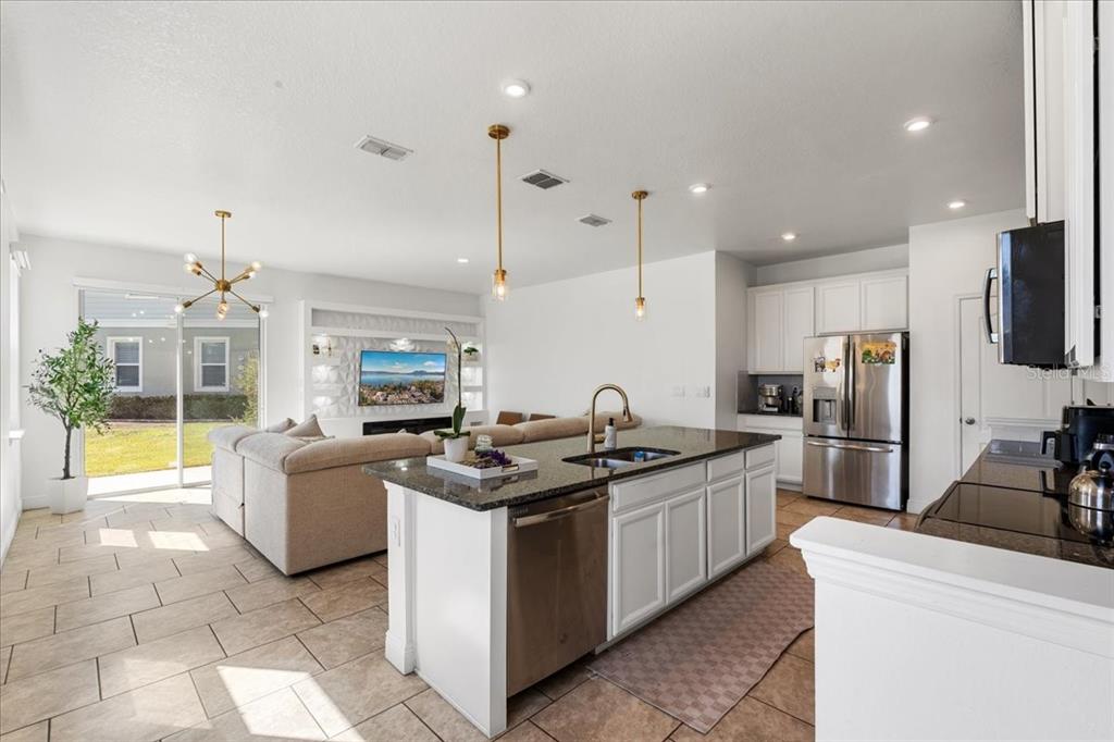 An open-concept kitchen and living area features a granite island, stainless appliances, and tile flooring — 2759 PLEASANT CYPRESS CIRCLE, KISSIMMEE, FL