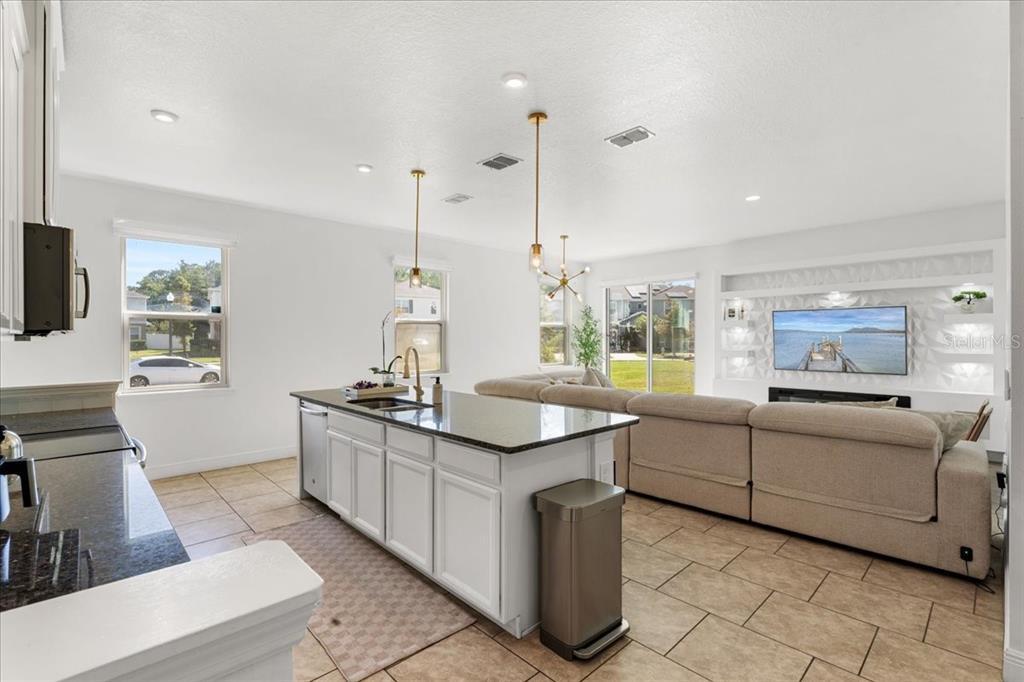 An open-concept kitchen with a granite island overlooks a living area with a large sofa — 2759 PLEASANT CYPRESS CIRCLE, KISSIMMEE, FL
