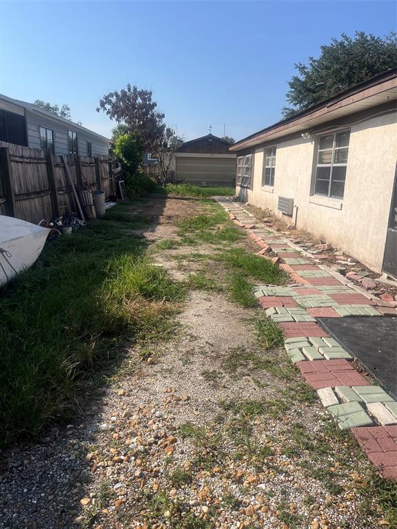 A side yard features a gravel path, a brick walkway, and a wooden fence — 214 INDIAN CREEK ROAD, OAK HILL, FL