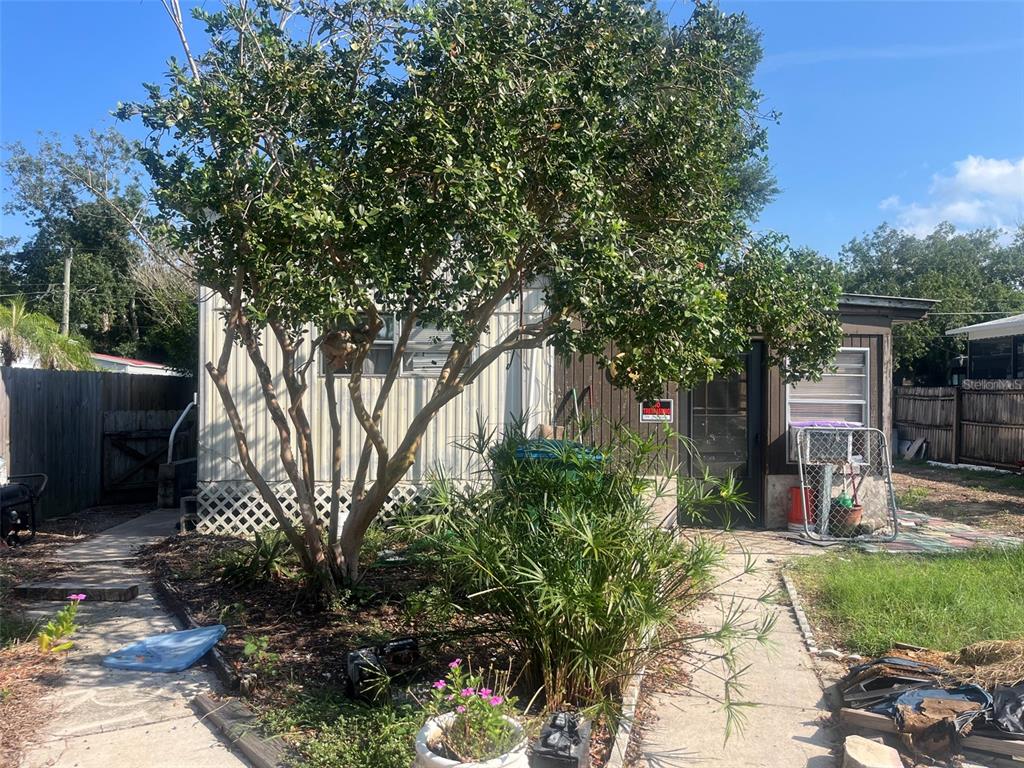 A single-story house exterior features a large tree, a concrete walkway, and a fenced yard — 214 INDIAN CREEK ROAD, OAK HILL, FL